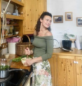 Photo of woman in kitchen making plant medicine with a pestle & mortar.