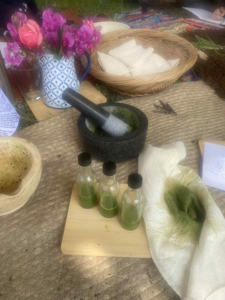 Pestle and mortar next to 3 glass vials of green plant medicine.
