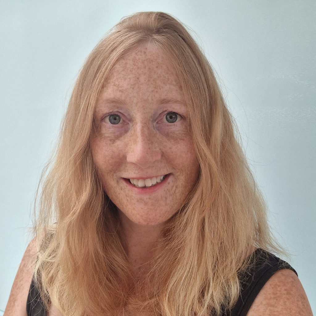 Photo of smiling woman with shoulder-length, blonde, wavy hair,