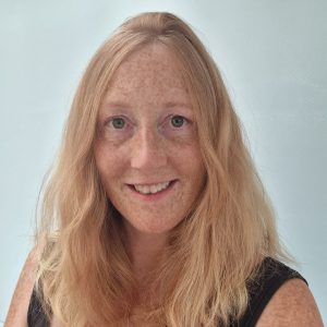 Photo of smiling woman with shoulder-length, blonde, wavy hair,